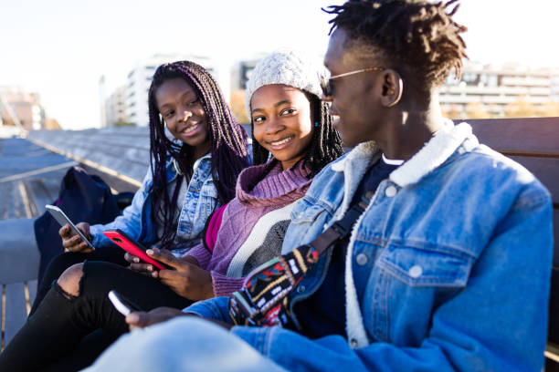 istock Group of three friends using mobile phone in the street. 908887304