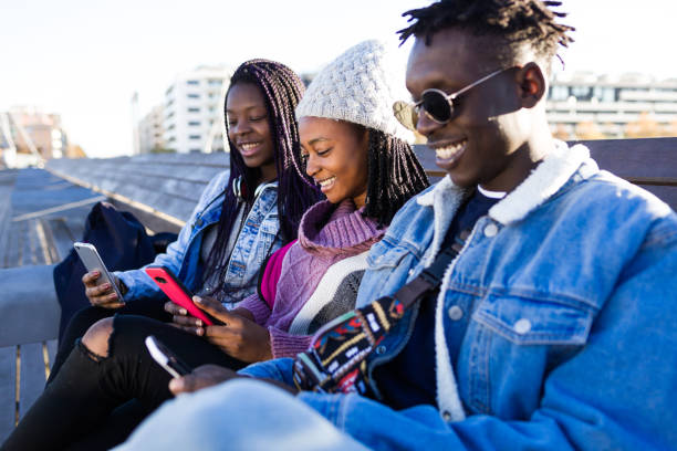 istock Group of three friends using mobile phone in the street. 908887634