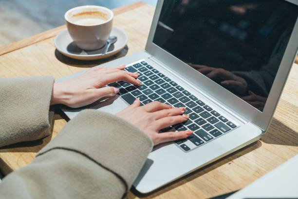 istock young woman using laptop in coffee shop,hands close up 908903354