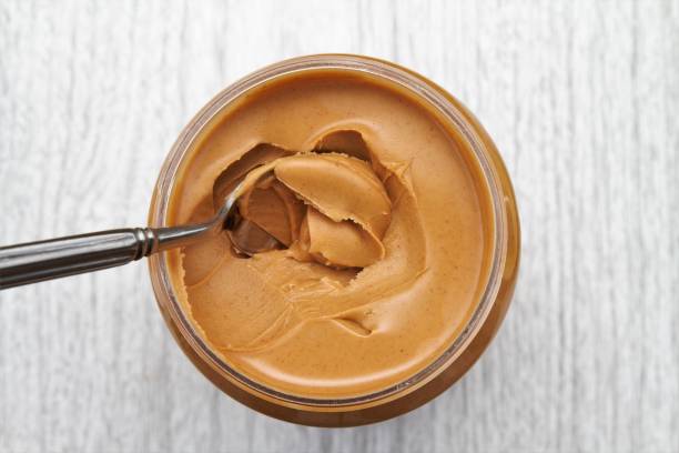 Peanut butter on spoon in jar stock photo