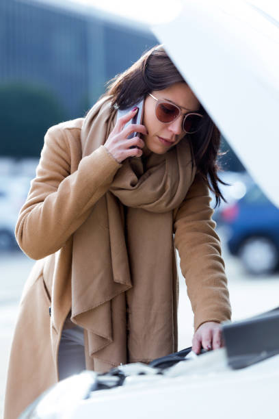 istock Beautiful young woman using her mobile phone calls for assistance for car. 908913802