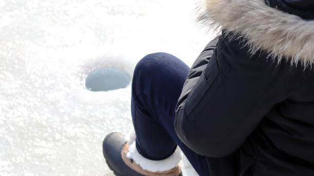 Trout Ice fishing festival at the winter. Sitting and looking at an ice hole. stock photo