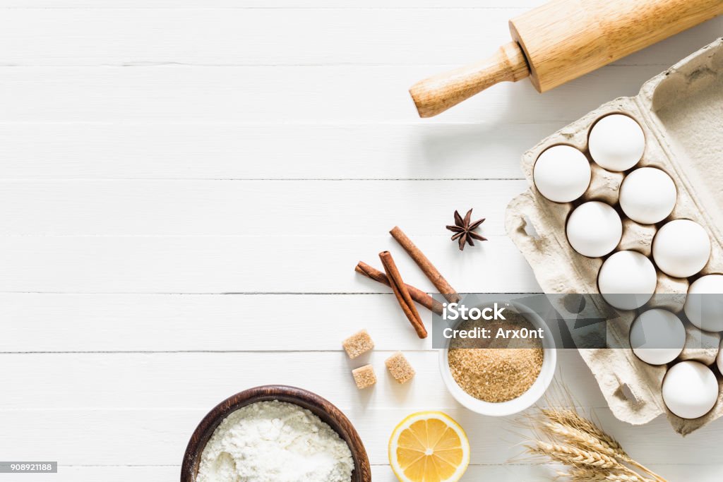 Baking ingredients on white table. Home baking concept Baking ingredients on white table. White eggs, rolling pin, flour, sugar and spices. Home baking concept, baking cake or cookies ingredients Baking Stock Photo