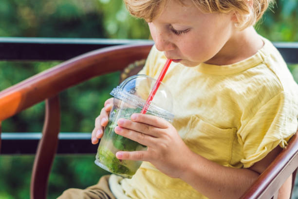 istock A little boy drinks water with mint and lime. Drink more water concept 908931802