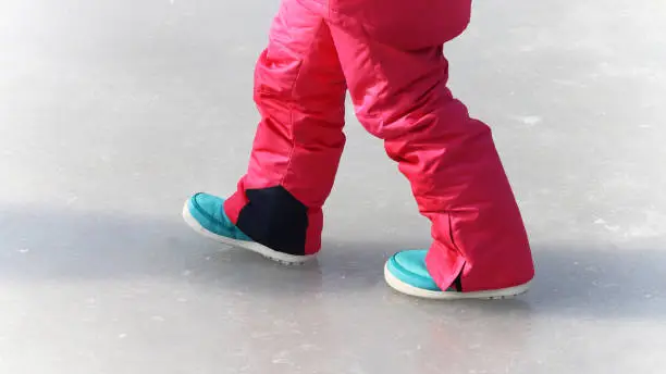 Photo of The legs of a girl walking on ice.