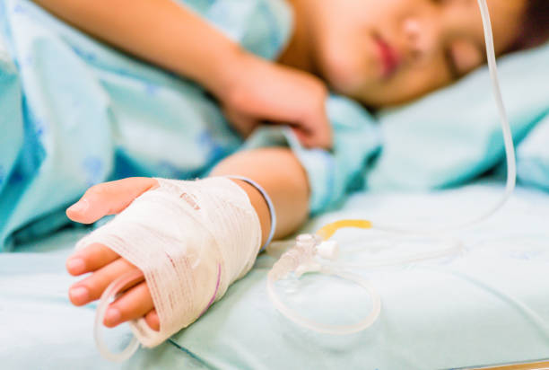 closeup kid hand  sleeps on a bed in hospital with saline intravenous. - infuse imagens e fotografias de stock