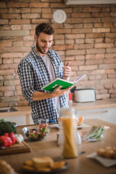 istock Happy man checking if he has everything from a cookbook for his lunch. 908939892