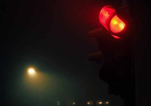 Closeup view of semaphore, red light and foggy night atmosphere.