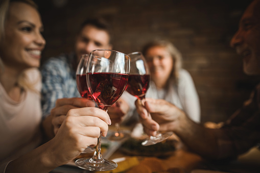 Close up of adult children and their parents toasting with wine at home.