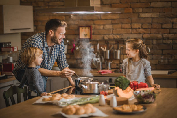 istock Single father and his small kids preparing lunch in the kitchen. 908943754