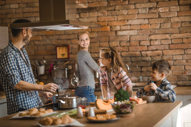 istock Young happy family communicating while preparing lunch together in the kitchen. 908944592