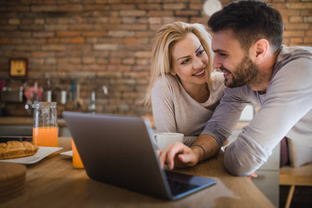 istock Happy couple in love using laptop in the kitchen. 908947260