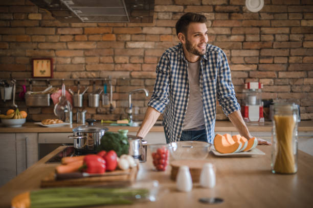 istock Young happy man about to prepare a meal in the kitchen. 908948438