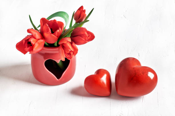 istock Two stone hearts and bunch of red tulips on white 908953184