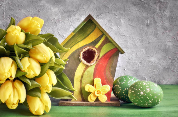 istock ellow tulips, birdhouse and painted Easter eggs with decorative felt flower. 908953186