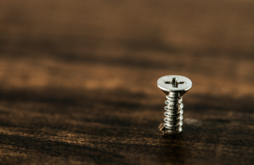 Macro shot of screw on wooden background