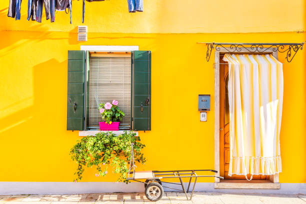 casa gialla con fiori e piante. case colorate nell'isola di burano vicino a venezia, italia. - beauty in nature bright building exterior close up foto e immagini stock