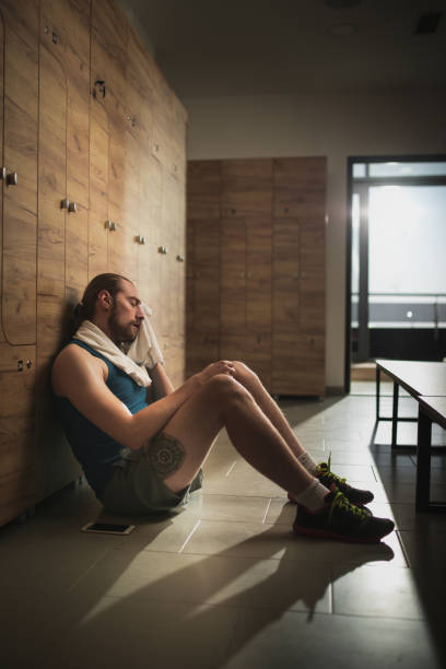 istock Exhausted athletic man wiping his sweat on a break in dressing room. 908959954