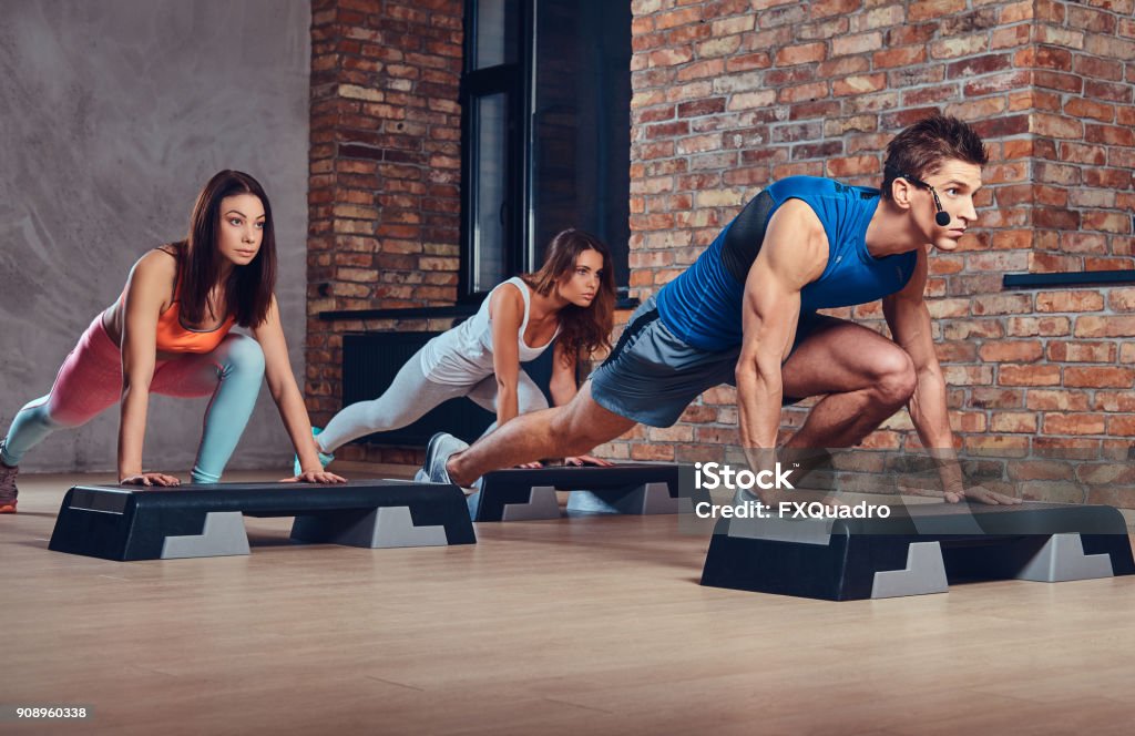 A man learning women how to do push ups. Male fitness coach learning women how to do push ups. Staircase Stock Photo