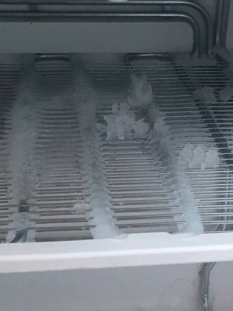 istock freezer compartment with an open door. The freezer covered with snow and ice is open for defrosting. In the refrigerator, snow and ice are melting, frozen on the walls and shelves. 908963330