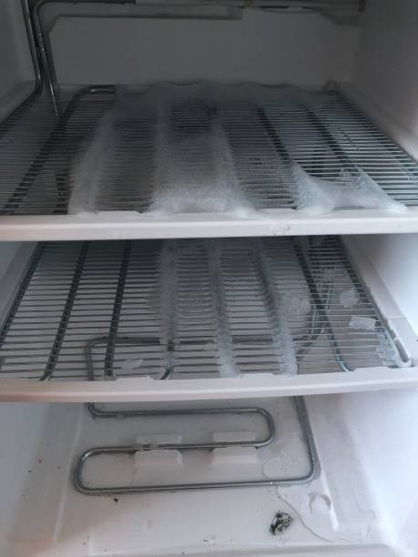 istock freezer compartment with an open door. The freezer covered with snow and ice is open for defrosting. In the refrigerator, snow and ice are melting, frozen on the walls and shelves. 908963352