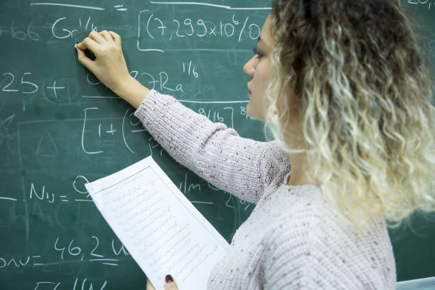 istock Female Student writing mathematical formula in front of the blackboard 908964562