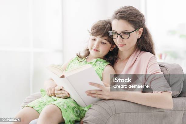 Mother And Daughter Reading Together Stock Photo - Download Image Now - Nanny, Teenager, Adult