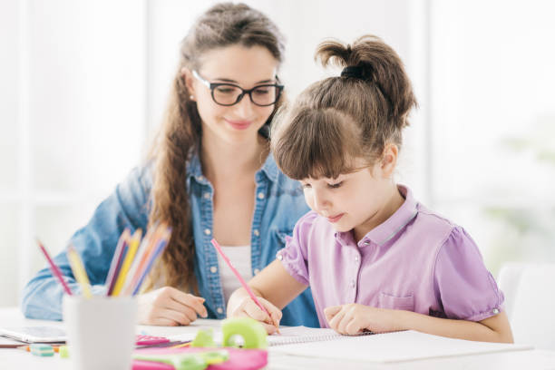 istock Teacher and girl drawing at school 908965580