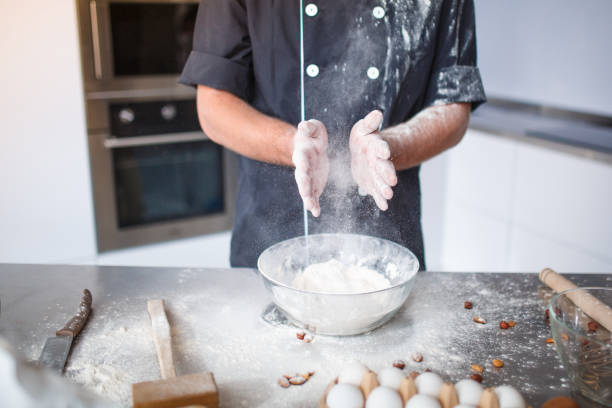 istock A man, , kneading dough, wringing flour from his hands over a deep bowl. Close-up. 908965614