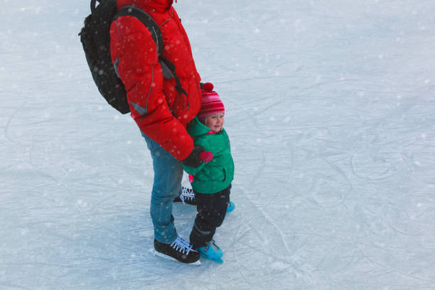 istock father and little daughter learning to skate in winter 908968674