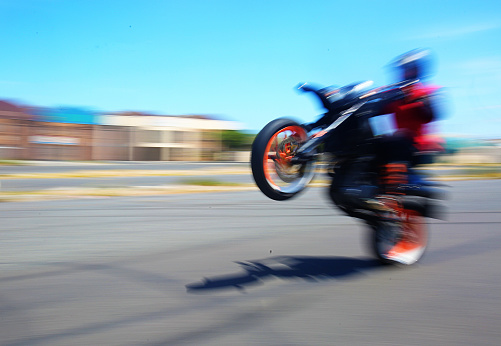 Biker pops a wheelie on asphalt  street with blurred motion