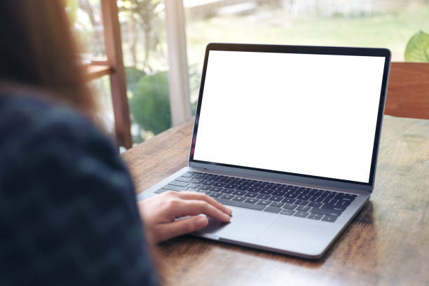 istock Mockup image of a hand using and touching laptop with blank white desktop screen on wooden table in cafe 908969706