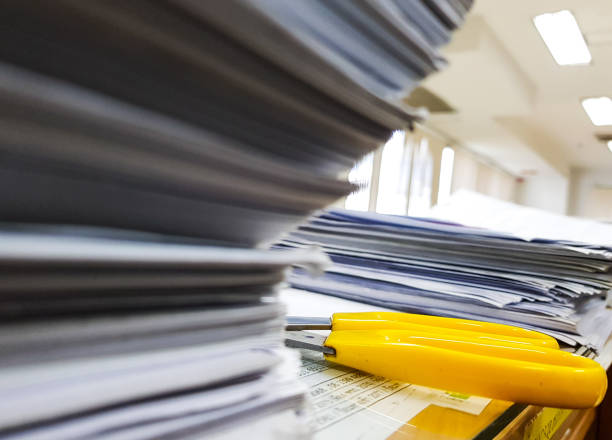 istock Yellow Scissors and Pile of documents on desk stack up high on Office background Concept 908970486