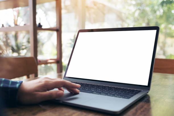 istock Mockup image of business woman using and touching on laptop with blank white desktop screen on wooden table in cafe 908973486