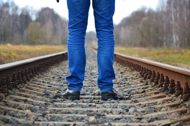 The legs of a man against the background of a railway track. View from the level of the rail.