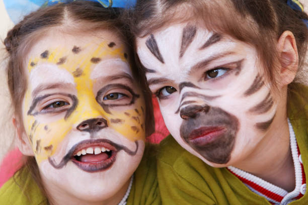 istock Little girls (twins) with faces painted like cheetah and zebra 908984736
