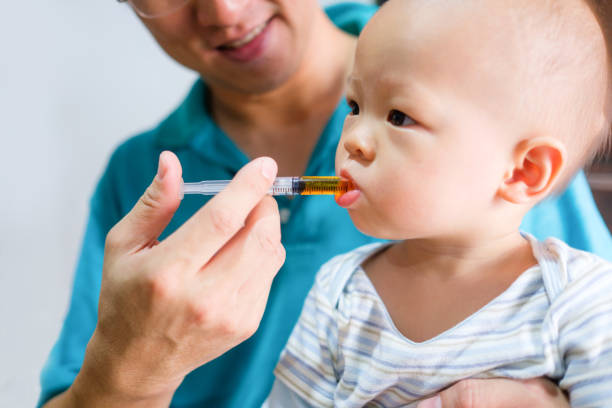 Cute little Asian 1 year old toddler baby boy child feeding with liquid medicine with a syringe, Dad giving remedy to kid who having flu Cute little Asian 1 year old toddler baby boy child feeding with liquid medicine with a syringe, Dad giving remedy to kid who having flu, child liquid medicine stock pictures, royalty-free photos & images