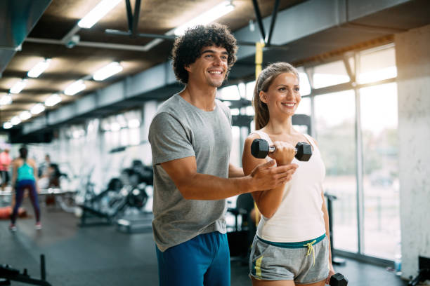 istock Young beautiful woman doing exercises with personal trainer 908986166