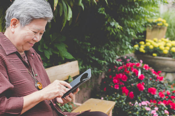 istock elder woman holding mobile phone in garden. elderly female texting message, using app with smartphone in park. senior use cellphone to connect with social network 908989108