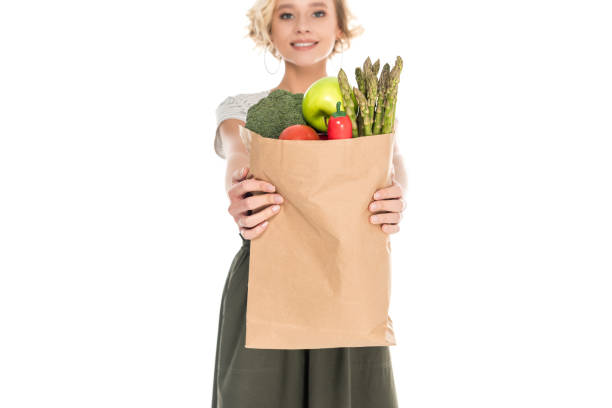 istock woman holding grocery bag and smiling at camera 908992724