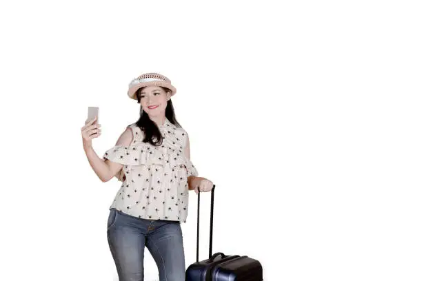 Picture of a Caucasian female tourist taking a selfie photo by using a smartphone, isolated on white background