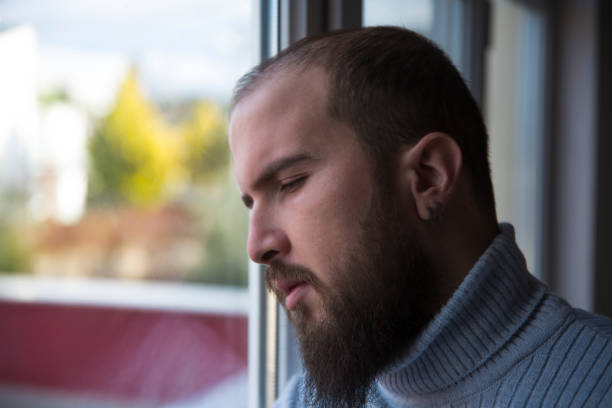 istock Young sad mad standing by the window 908993892