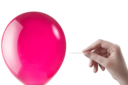 A pin being used to pop a redn balloon