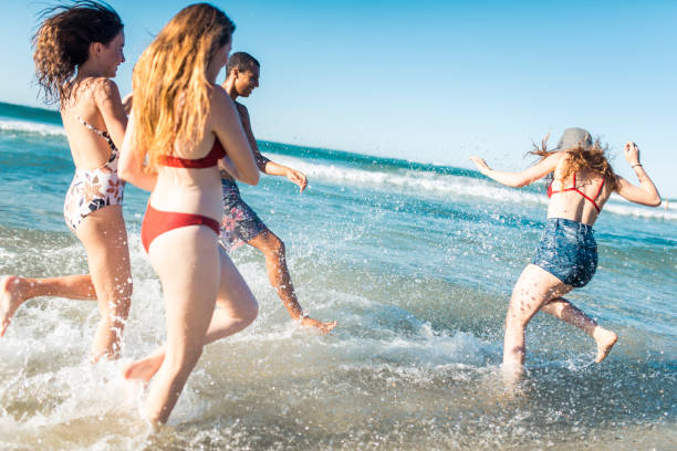istock Small group of people running into the ocean 909000028