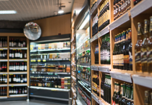 Blurred image of shelves with alcoholic drinks in supermarket.