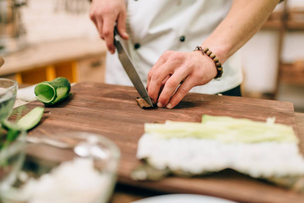 istock Male cook making sushi rolls on wooden table 909010796
