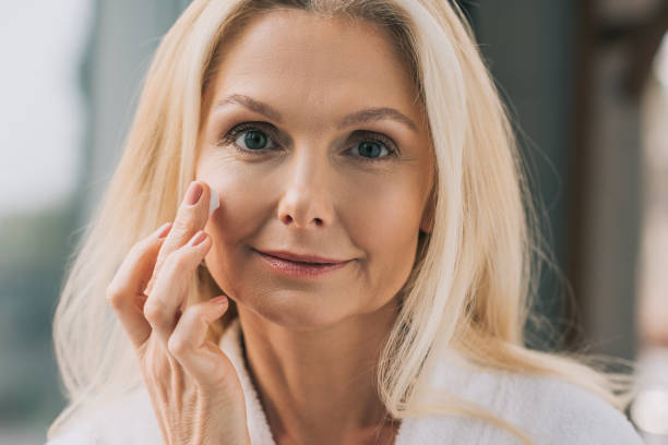 istock mature woman applying cosmetic cream 909011218