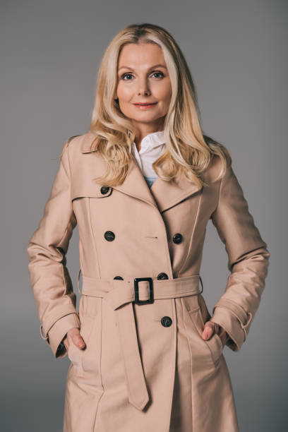 mature woman in trench coat attractive mature woman in trench coat isolated on grey middle aged woman fashion stock pictures, royalty-free photos & images