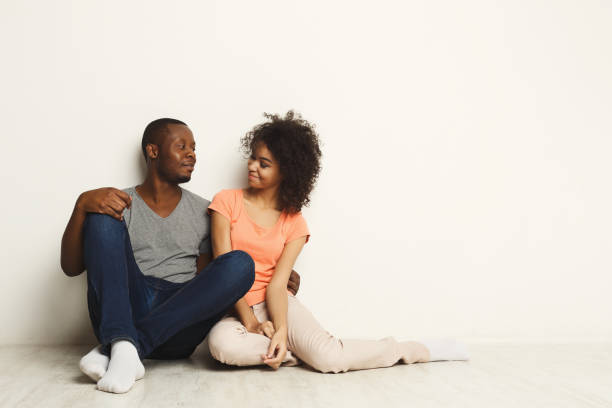 istock African-american couple looking up, sitting on floor 909031868