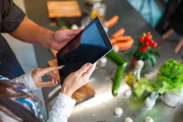 istock The guy and girl are standing in the kitchen and using a tablet. Close-up. 909032694
